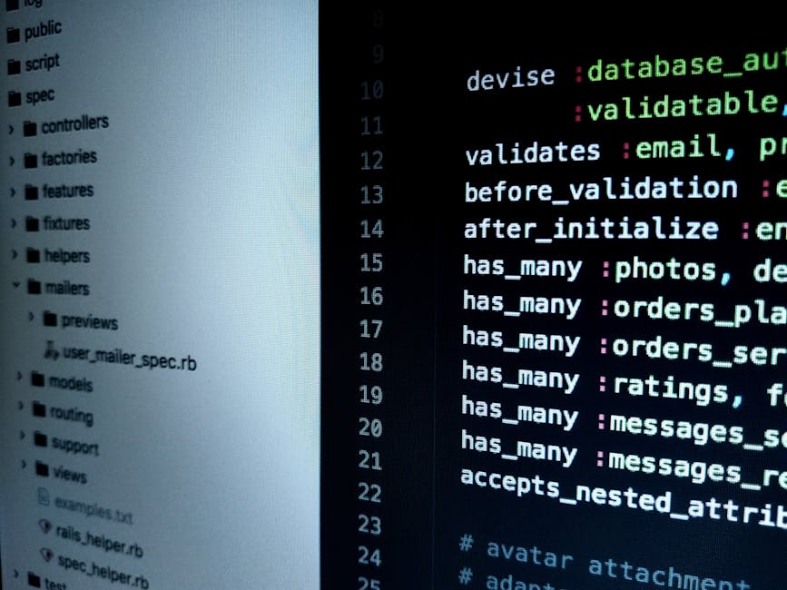 A person's hand with a wristwatch is typing on a laptop keyboard displayed on a wooden surface. The laptop screen shows lines of code or scripting text, indicating activity related to programming or w